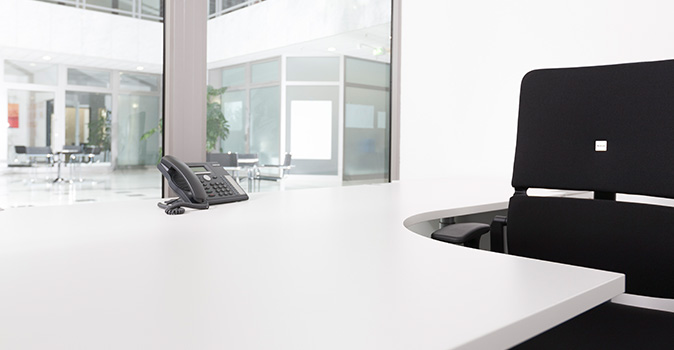 Helles Büro mit weißem Tisch und schwarzen Bürostuhl